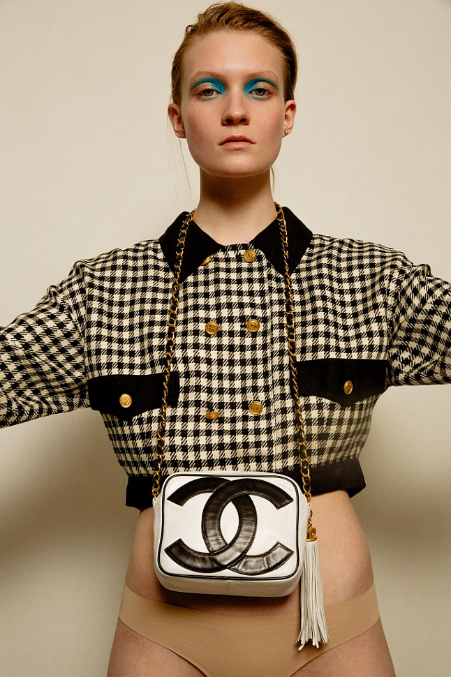 Model wearing Chanel short plaid jacket and Chanel black and white logo bag.