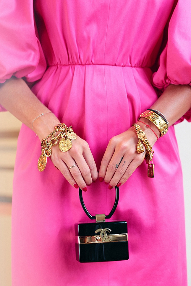 Elena wearing Yves Saint Laurent pink dress, Chanel logo pendant necklace, Chanel cuff, Chanel baroque charm bangle, Chanel logo bangle and Chanel rare lucite minaudière.