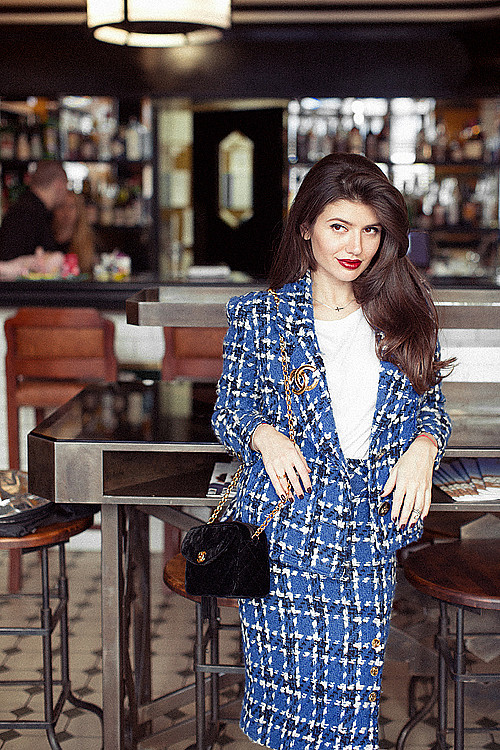 Vogue social editor, the lovely Maria Mikhailova, wearing a vintage tweed Chanel suit accessorized with a Chanel brooch and a velvet Chanel handbag.
